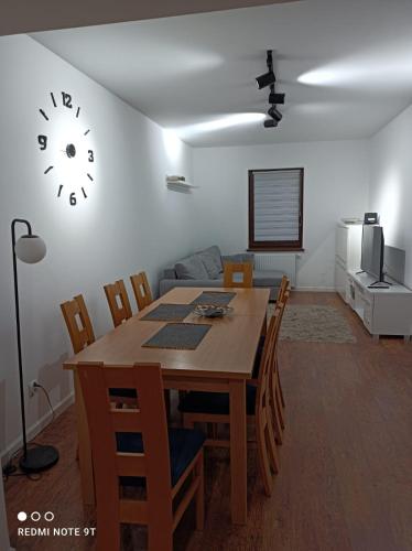 a dining room with a table and a clock on the wall at Apartamenty Sępopol in Sępopol