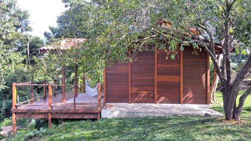 una cabaña de madera en un patio con un árbol en Casa de Montanha na Praia, en Ilhabela