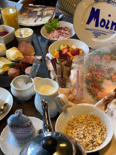 a table topped with bowls and plates of food at Schumacher's Landhaus - Bücherhotel in Friedeburg