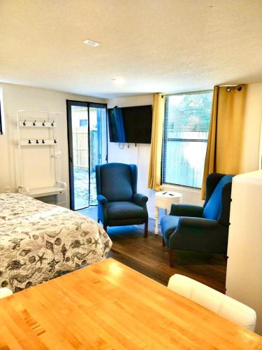 a bedroom with two chairs and a bed and windows at Two Fully Equipped Apartments and a Studio 5 miles from the beach in St. Petersburg