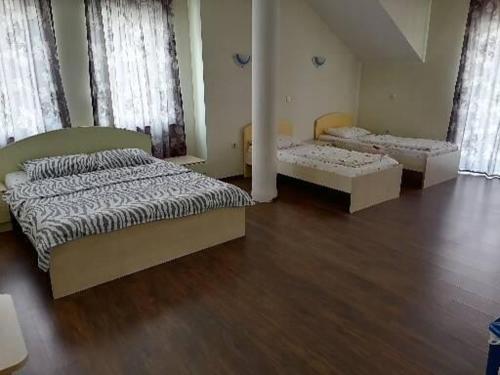 twee bedden in een kamer met houten vloeren en ramen bij CentrRooms-DS in Struga