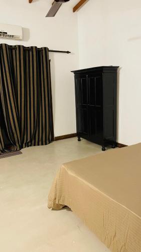 a room with a bed and a black dresser at Sea Sands Beach Hostel in Negombo