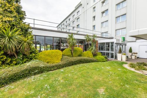 a building with a lawn in front of a building at Holiday Inn Basildon by IHG in Basildon