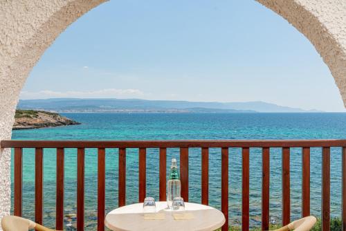 a table on a balcony with the ocean in the background at Hotel Punta Negra in Alghero