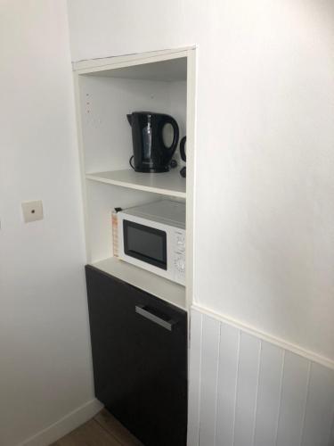 a small kitchen with a microwave on a shelf at Authentique maison de pêcheur à Port-en-Bessin in Port-en-Bessin-Huppain