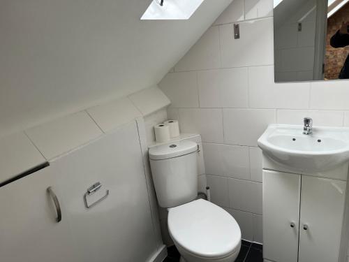 a white bathroom with a toilet and a sink at North West Lodge Guest House in London