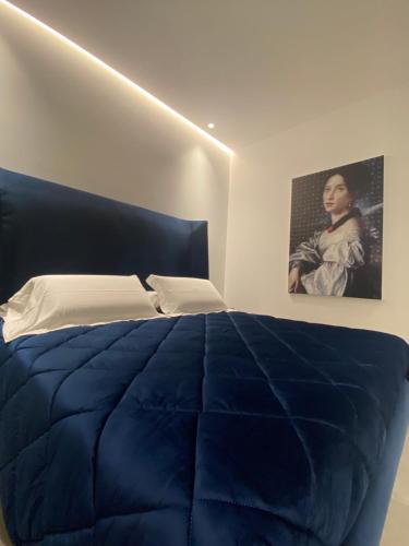 a bedroom with a blue bed with a picture on the wall at IL DUCA HOUSE e HOLIDAY PRESTIGE in Caccamo