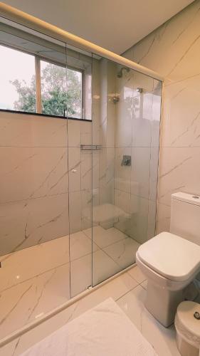 a bathroom with a glass shower with a toilet at Verde Vale Hotel in Videira