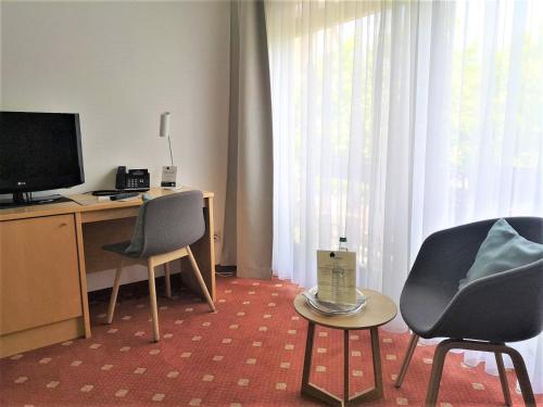 a room with two chairs and a desk with a television at Hotel Lindenhof Hubmersberg in Pommelsbrunn