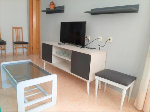 a white entertainment center with a tv and a chair at apartamento soleado, 1 dormitorio con balcón, piscina y garage in Torrevieja