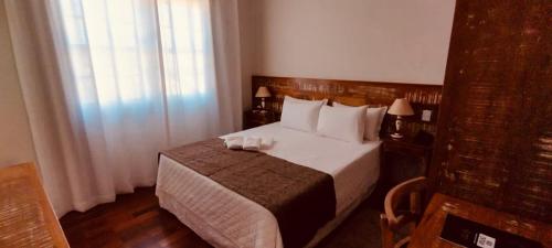 a hotel room with a bed and a window at Pousada Ouro de Minas in Tiradentes