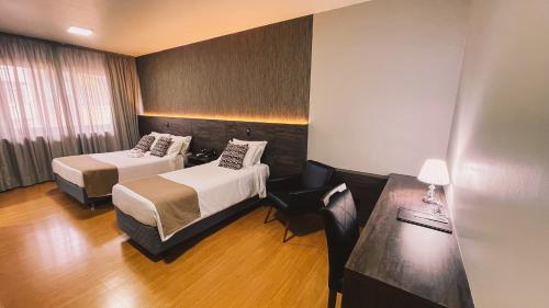 a hotel room with two beds and a table at Verde Vale Hotel in Videira