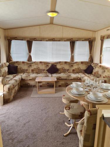 a living room with couches and a table and chairs at Superb 8 Berth Caravan, Golden Anchor Park in Chapel Saint Leonards