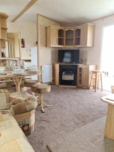 a living room with tables and a kitchen with a fireplace at Superb 8 Berth Caravan, Golden Anchor Park in Chapel Saint Leonards