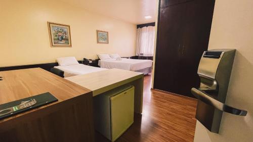 a hotel room with two beds and a desk at Verde Vale Hotel in Videira
