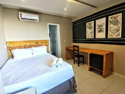 a bedroom with a large bed and a desk at Vila Aju - Pousada Temática in Aracaju