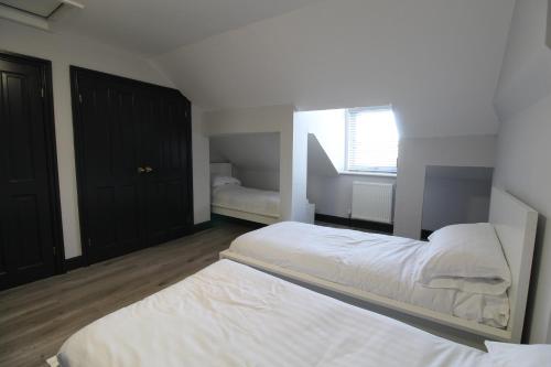 a white bedroom with two beds and a window at Anfield house in Liverpool