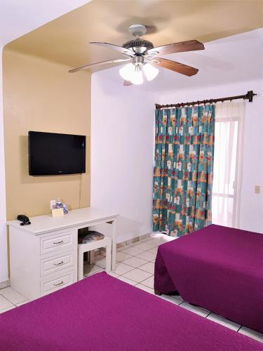 a bedroom with a bed and a desk with a tv at Hotel Costa Brava in Manzanillo