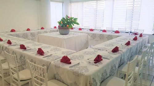 a room with tables and chairs with red roses on them at Hotel Costa Brava in Manzanillo