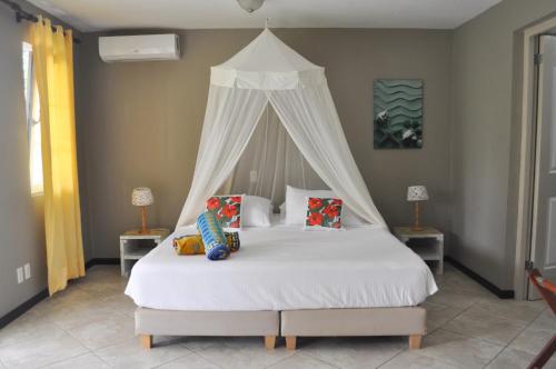 a bedroom with a white bed with a canopy at Hibiscus Beach House in Willemstad