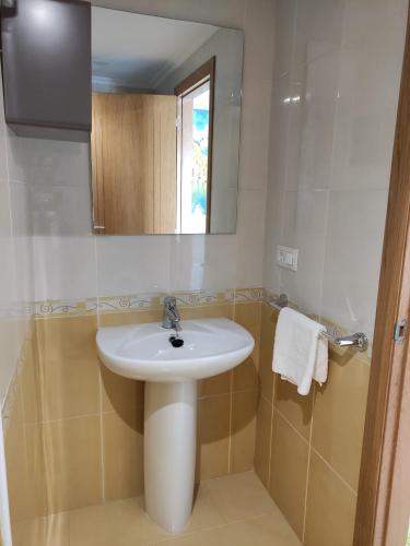 a bathroom with a white sink and a mirror at The Way Apartamento in O Pedrouzo