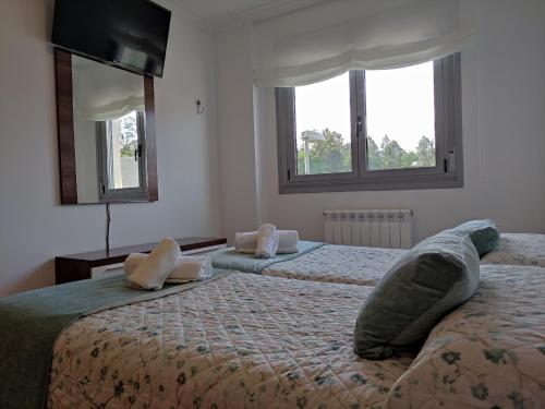 two beds in a room with two windows at The Way Apartamento in O Pedrouzo