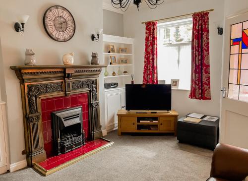 ein Wohnzimmer mit Kamin und Fernseher in der Unterkunft Thisledo Holiday Cottage - Dog-friendly cosy cottage, 5 min walk to Skipton town centre in Skipton