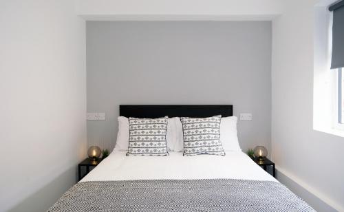 - une chambre avec un lit doté de draps et d'oreillers blancs dans l'établissement The Kop End Hotel by Serviced Living Liverpool, à Liverpool
