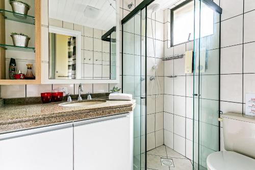 uma casa de banho com um chuveiro, um lavatório e um WC. em Apto com sacada e churrasq 100m Praia Brava COI302 em Florianópolis