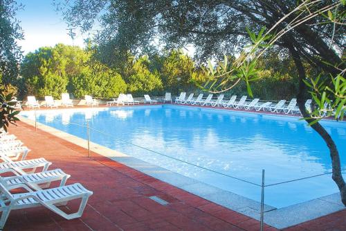 una piscina con sillas blancas y un montón de latas en Holiday residence Sa Jaga Brujada in Porto Rotondo, en Porto Rotondo