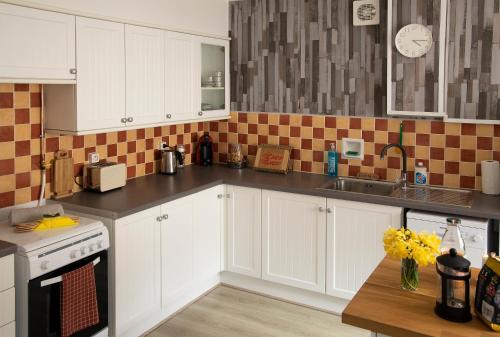 a kitchen with white cabinets and a sink at Le Balcon Bleu, gîte located in Millevaches National Park in Chavanac