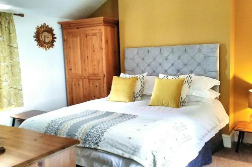 a bedroom with a large white bed with yellow walls at Wells Cottage in Malvern Wells