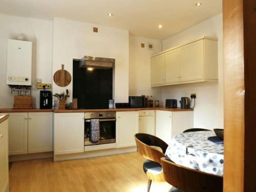 uma cozinha com armários brancos e uma mesa com cadeiras em Wells Cottage em Malvern Wells