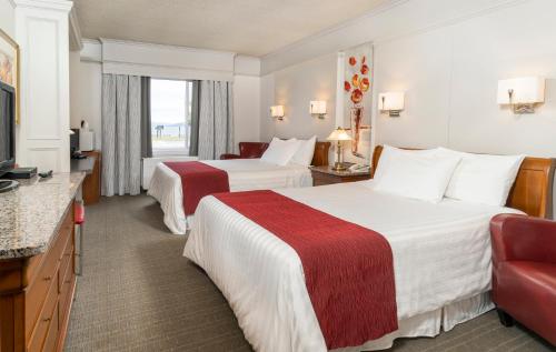 a hotel room with two beds and a television at Auberge des 21 in La Baie