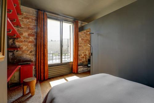 um quarto com uma cama e uma grande janela em Appartement artiste atelier bail mobilité Palais Royal em Paris
