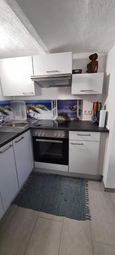 a kitchen with white cabinets and a black oven at byJoe in Morschen