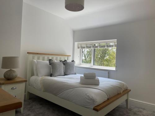a white bedroom with a bed with a window at Forest View in Coed Ely