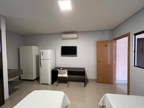 a kitchen with two refrigerators and a table and a refrigerator at Suites Stival Centro in Goiânia