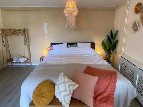a bedroom with a large white bed with pillows at Bed en Koffie Casa Mañana de Koog in De Koog