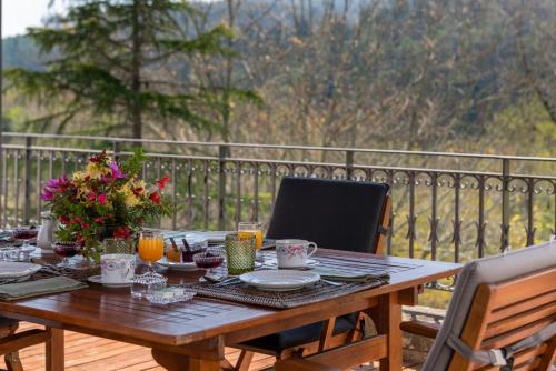 a wooden table with plates and flowers on a deck at Quinta de Mourães Casa dos Rododendros in Lever