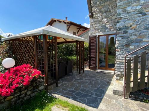 a patio with an umbrella and flowers next to a building at Casa Cinzia in Gravedona