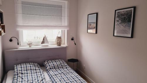 1 dormitorio con 1 cama con 2 almohadas y ventana en Apartament Klifowa Rewal 16, en Rewal