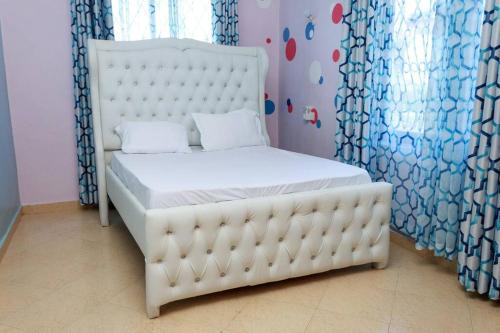SERENE 4 BEDROOMED HOME IDEAL FOR FAMILY HOLIDAY في مومباسا: سرير أبيض في غرفة بها نافذة