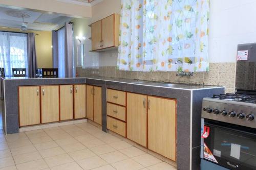SERENE 4 BEDROOMED HOME IDEAL FOR FAMILY HOLIDAY في مومباسا: مطبخ بدولاب خشبي وفرن علوي موقد