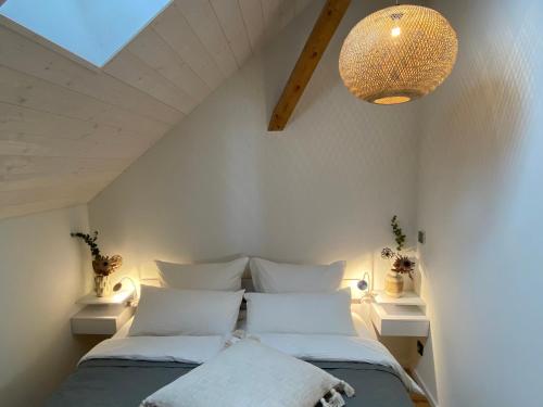 Schlafzimmer mit einem Bett mit weißen Kissen und einem Kronleuchter in der Unterkunft Ferienwohnung d.d. Chalet in Aitrach