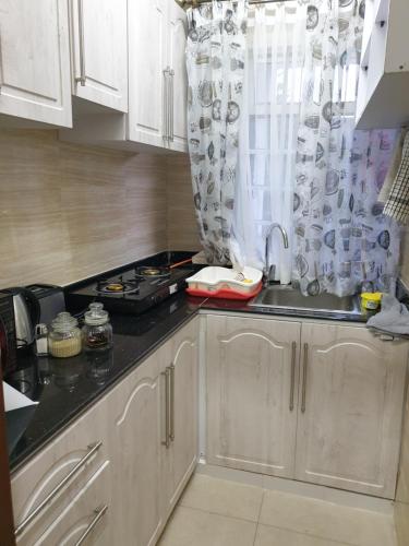 a kitchen with white cabinets and a sink at Lovely 2 and 1 bedroom guest units Karen in Nairobi