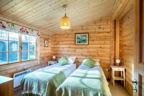 a bedroom with two beds in a log cabin at Willowbank Lodges in Oare