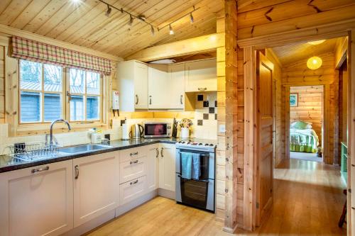 a kitchen with white cabinets and a wooden ceiling at Willowbank Lodges in Oare
