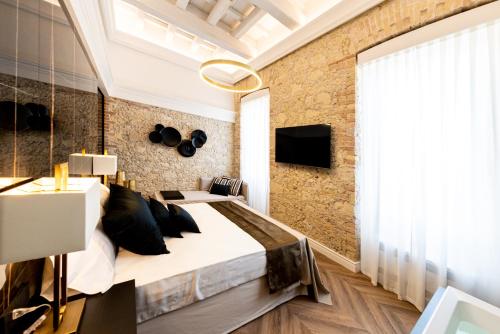 a bedroom with a large bed and a brick wall at Nero Luxury Suites in Cagliari