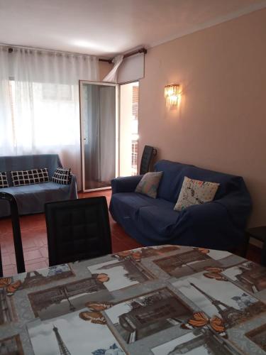 a living room with a blue couch and a table at Club Nautic in Cambrils